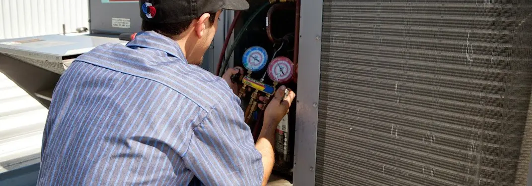 HVAC technician servicing a condenser unit in Thomas