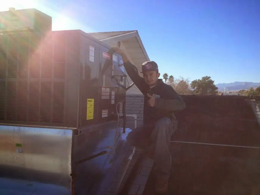 HVAC technician performing AC Tune-Up on a rooftop unit in Thomas